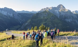 A group of hikers enjoys the view of the mountains. The sky is clear, and nature provides an impressive backdrop. | © OK-Bergbahnen