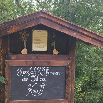 Ein traditionelles Holzschild mit der Aufschrift "Herzlich Willkommen an den Ötztal". Umgeben von grünen Bäumen und einer ländlichen Umgebung. | © Nicole Lughammer