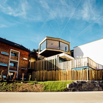 © Genuss- und Aktivhotel Sonnenburg | Andi Mayr Ein modernes Gebäude mit Holzverkleidung und großen Fenstern. Die Architektur kombiniert traditionelle und zeitgenössische Elemente. | © Genuss- und Aktivhotel Sonnenburg | Andi Mayr