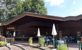 Ein gemütliches Café mit einer Holzfassade und überdachten Sitzbereichen. Umgeben von Pflanzen und einer einladenden Außenterrasse. | © Kulturcafe Riezlern | Veronika Senn