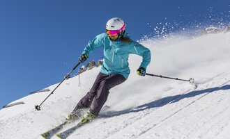 A skier is riding on a snowy slope. The clear blue sky and the snow create a beautiful winter atmosphere. | © GENUSS & AKTIVHOTEL SONNENBURG
