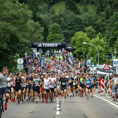 Ein großes Laufereignis mit vielen Teilnehmern, die auf einer Straße starten. Im Hintergrund sind Bäume und eine Startlinie sichtbar. | © Kleinwalsertal Tourismus - Dominik Berchtold