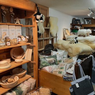 A cozy shop with wooden shelves full of handmade products. In the background, there are high-quality wool products and decorations. | © Abler Mitbringsel Riezlern | Veronika Senn