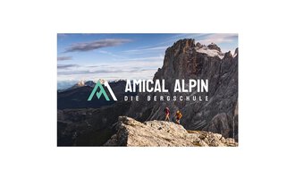 Two people are hiking on a rock with a view of impressive mountains. The logo of "Amical Alpin" is prominently placed in the image. | © SALEWA | Fotograf Storvteller Labs