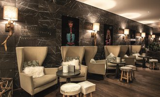 A modern café with cozy seating areas and stylish decor. The walls are decorated with artistic pictures, and there is soft lighting. | © Travel Charme Ifen Hotel