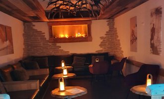 Ein gemütlicher Raum mit einer warmen Atmosphäre. Es gibt bequeme Sitze und sanftes Licht von Kerzen. | © Hotel Steinbock