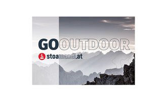 An impressive mountain landscape in the background with gentle hills and a gray sky. In the foreground is the inscription "GO OUTDOOR" as well as the logo of stoamandl.at. | © stoamandl