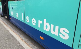 A bus with the inscription "walserbus". The color of the bus is mainly green and blue. | © Kleinwalsertal Tourismus