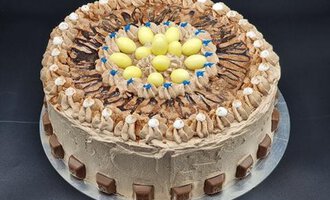 A decorative chocolate cake with colorful topping and a creation of cream. It is decorated with small chocolate pieces and colorful eggs.