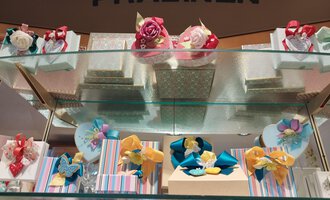 Gift wraps with colorful ribbons and chocolates are arranged on a shelf. The shelf is adorned with various decorations. | © Kleinwalsertal Tourismus | N. Lughammer
