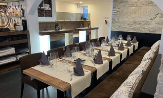 An elegantly set table in a restaurant with dark chairs and decorated napkins. The room has a modern, welcoming atmosphere.