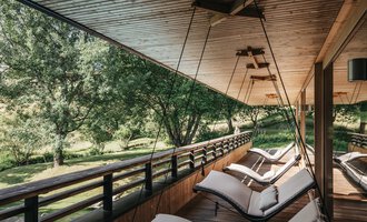 Eine entspannende Veranda mit modernen Liegen und Blick auf einen grünen Garten. Die Holzdecke und die natürliche Umgebung schaffen eine ruhige Atmosphäre. | © Naturhotel Chesa Valisa | Heldentheater
