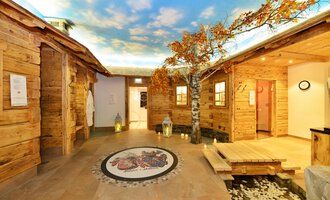 Ein gemütlicher Wellnessbereich mit Holzverkleidungen und einer schönen Baumdekoration. Die Decke zeigt einen klaren Himmel, der eine entspannende Atmosphäre schafft. | © Hotel Alpenstüble Appartements | Manuel Riezler