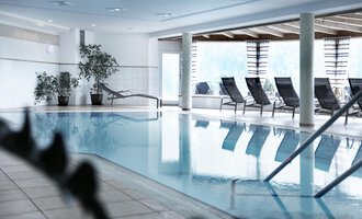 Ein heller Innenpool mit Liegen und Pflanzen. Der Raum ist modern und einladend gestaltet. | © Hotel Birkenhöhe