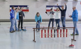 Eine Gruppe von Menschen feiert auf einer Curling-Bahn. Sie zeigen Freude und Enthusiasmus beim Spiel. | © Sportstätten Oberstdorf | Marc Vogel