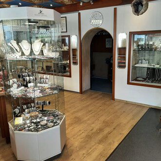 Ein Juweliergeschäft mit einem Schmuckdisplay in der Mitte. An den Wänden sind weitere Schmuckstücke in Vitrinen ausgestellt. | © Juwelier Demsky Walser Goldschmiede| Veronika Senn