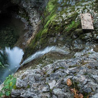 A rocky cliff with flowing water that leads into a deep, dark pool. Green moss and plants grow between the stones. | © Kleinwalsertal Tourismus | Andre Tappe