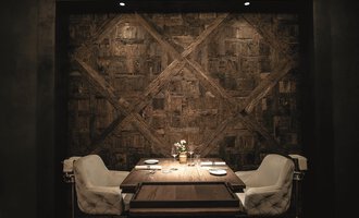 An elegant dining room with a table and two white chairs. The wall in the background is made of wood and gives the room a warm atmosphere. | © Travel Charme Ifen Hotel