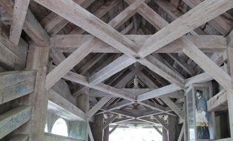 An old bridge with a wooden roof and visible struts. The interior is bright and leads to an open end. | © Stefan Heim