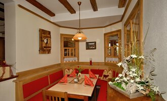 A cozy restaurant area with red upholstery and a wooden parlor design. The warm lights and the decor create an inviting atmosphere. | © Michl das Steakhaus | Johannes Littich