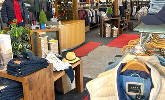 A modern clothing store with a bright, inviting atmosphere.  
Shelves full of clothing and accessories are well arranged to provide customers with a pleasant shopping experience. | © Moosbrugger Mode e.U.