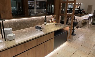 A modern bar with an elegant wooden and stone counter. The space is well-lit and offers a cozy atmosphere. | © Almhof Rupp | Lukas Kind