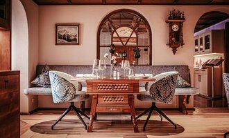 A cozy restaurant with a stylish table and elegant chairs. The room has a warm atmosphere with wooden details and decorative elements.