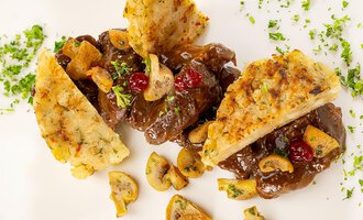 A delicious dish with pieces of meat in a dark sauce, garnished with mushrooms and cranberries. Crispy side dishes are served alongside. | © Hotel Alte Krone
