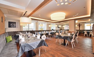 Ein elegantes Restaurant mit Holzfußboden und modernen Tischen. Die Tische sind schön gedeckt und die Beleuchtung ist sanft. | © Hotel Neue Krone GmbH | Werbewind GmbH