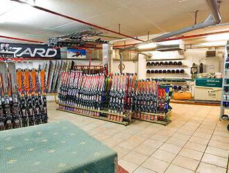 A ski rental shop with many skis and snowboards in a well-organized space. The walls are covered with equipment and accessories for winter sports. | © Aparthotel Kleinwalsertal Haller GmbH & Co KG