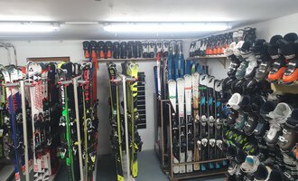 A room with several skis and ski boots, neatly stacked on shelves. The lighting is bright and it looks like a ski rental. | © IFA Hotel Alpenrose