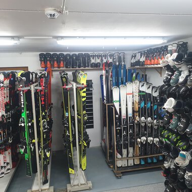 Ein Raum mit mehreren Skiern und Skischuhen, ordentlich gestapelt auf Regalen. Die Beleuchtung ist hell und es sieht nach einem Ski-Verleih aus. | © IFA Hotel Alpenrose