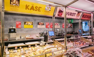 A cheese and sausage stand in a store. The display showcases a wide variety of cheeses and meat products. | © SPAR