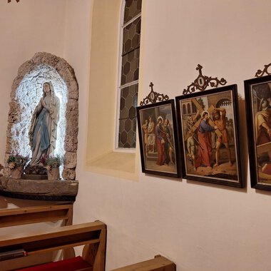 A church gallery with a statue of Mary and several historical paintings on the wall. The atmosphere is peaceful and reverent. | © Unterwestegg-Kapelle Maria Hilf | Tanja Ritsch