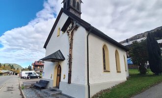 A small church with a pointed tower and large windows. The sky is partly cloudy and the surroundings are green and well-kept. | © Unterwestegg-Kapelle Maria Hilf | Tanja Ritsch