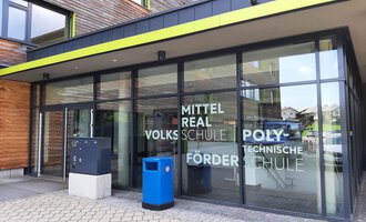 A modern school building with large windows. The entrance facade displays the labeling of different types of schools. | © Kleinwalsertal Tourismus | Veronika Senn